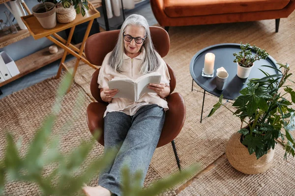 Senior Kvinna Läser Bok Njuter Tid Ensam Sin Lägenhet — Stockfoto
