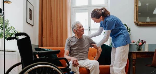 Young Nurse Helping Senior Man Stand Sofa — Stock Photo, Image