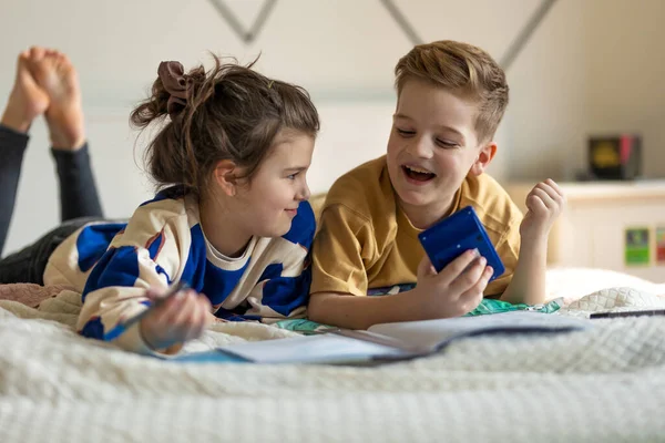 Küçük Çocuklar Yatağa Uzanıp Ödevlerini Yapıyorlar — Stok fotoğraf