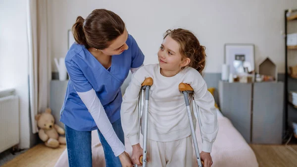 年轻的护士帮助断腿的小女孩走路 — 图库照片