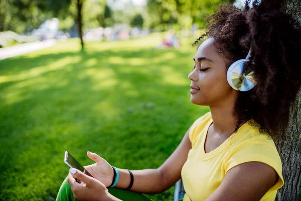 Multiracial Girl Sitting Grass Enjoying Music Headphones Side View — Zdjęcie stockowe