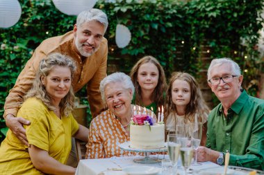 A multi-generation family on outdoor summer garden party, celebrating birthday