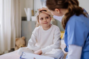 Hastane odasında küçük bir kıza bakan genç bir doktor..