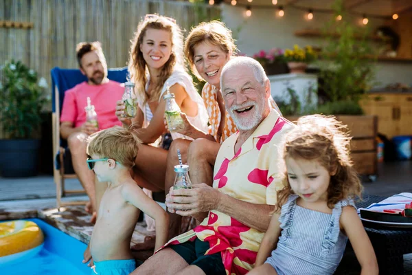 一个多代家庭享受夏天的时光 坐在后院游泳池边 — 图库照片