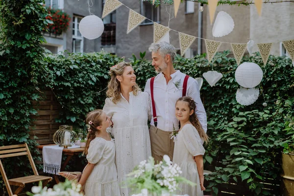 熟女花嫁と新郎ポーズとともに彼らの娘で結婚式レセプションで裏庭の外 — ストック写真
