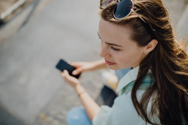 都会のアウトドアスマートフォンを持つ若い女性の高い角度ビュー — ストック写真