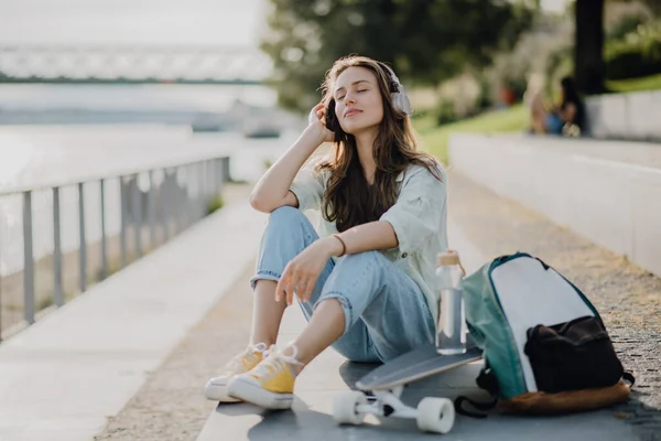 幸せな若い女性が街に座って音楽を聴いている 若者文化と通勤概念 — ストック写真