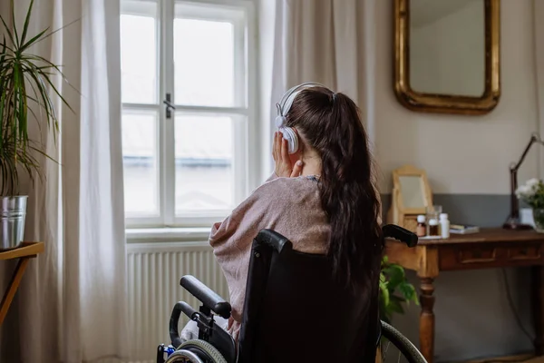 Nastolatka Siedząca Wózku Inwalidzkim Słuchająca Muzyki Wyglądająca Przez Okno — Zdjęcie stockowe