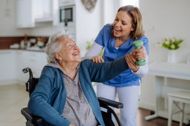 Hemşire, yaşlı kadınla evinde egzersiz yapıyor. Sağlık ve rehabilitasyon kavramı..