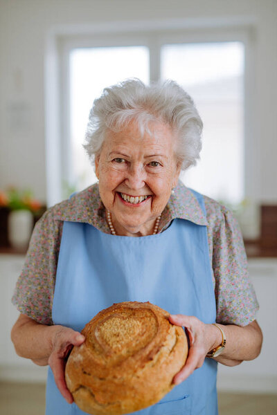 Portrait of senior woman with a fresh baked bread.