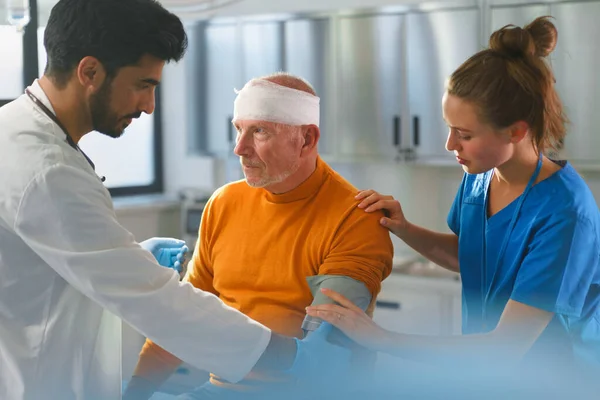 Junger Arzt Und Krankenpfleger Behandelt Verletzten Kopf Eines Seniors — Stockfoto