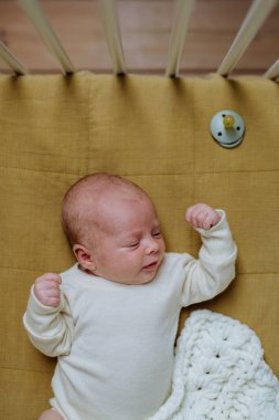 Küçük yatakta uyuyan yeni doğan bebek manzarası.