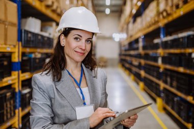 Manager woman in suit controlling goods in warehouse. clipart