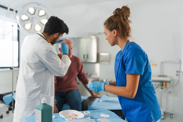 Joven Médico Enfermera Tratando Cabeza Lesionada Del Hombre Mayor — Foto de Stock