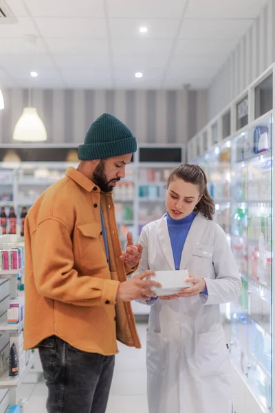 Mladý Lékárník Pomáhá Zákazníkovi Vybrat Lék — Stock fotografie