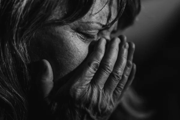 Close-up of sad elderly woman, black and white photo.