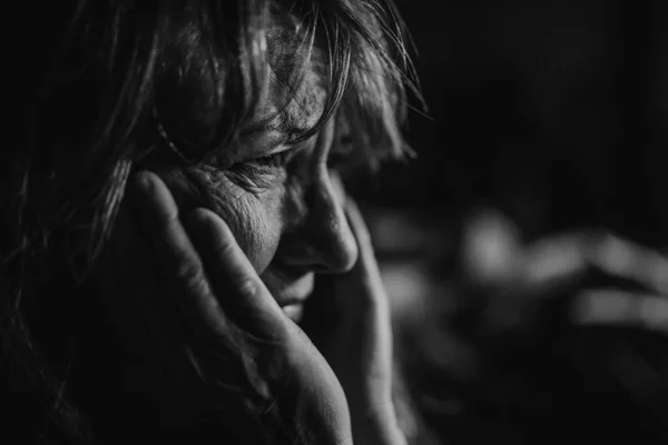 Close-up of sad elderly woman, black and white photo.