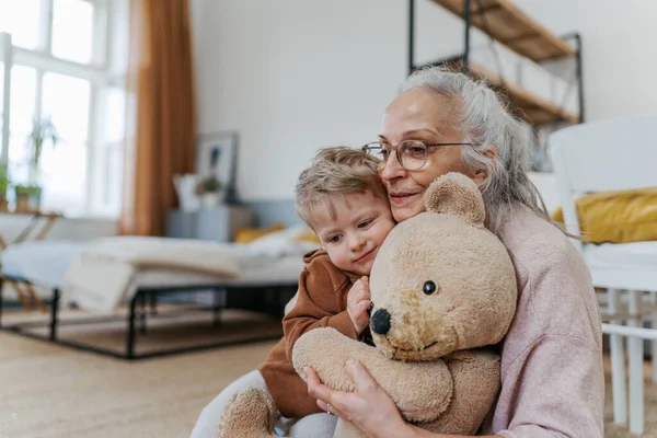 Avó Abraçando Seu Neto Com Brinquedo Urso — Fotografia de Stock