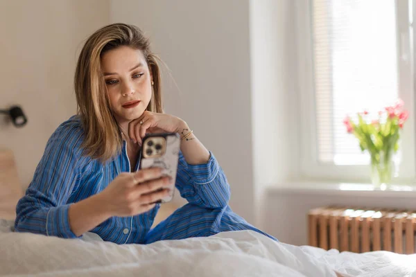 Genç Bir Kadın Yatağında Uzanıyor Akıllı Telefonu Kaydırıyor — Stok fotoğraf