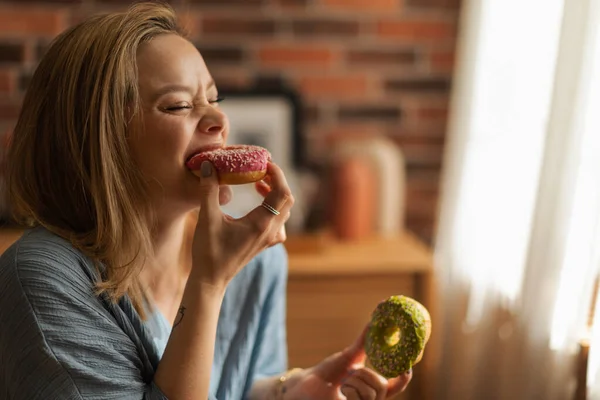 若いです幸せな女性食べるドーナツでザカフェ — ストック写真