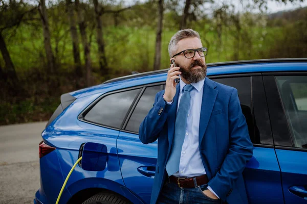 Reifer Geschäftsmann Wartet Auf Das Laden Seines Neuen Elektroautos — Stockfoto