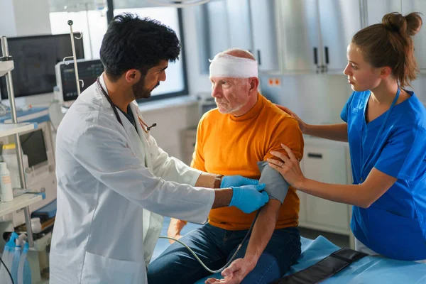 Joven Médico Enfermera Tratando Cabeza Lesionada Del Hombre Mayor — Foto de Stock
