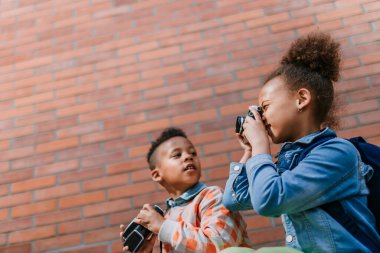 Multiracial siblings taking photos outdoor, enjoying holiday.