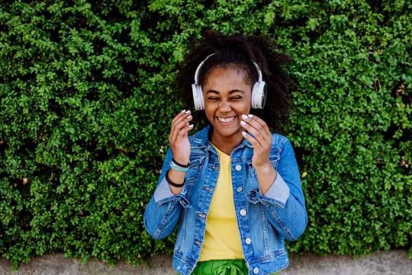 Multiracial Girl Enjoying Music Headphones Standing Front Green Bush Portrait — Zdjęcie stockowe