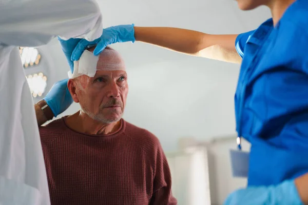 Închiderea Medicului Asistentei Medicale Care Tratează Capul Rănit Unui Bărbat — Fotografie, imagine de stoc