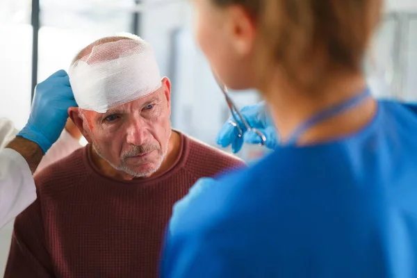 老人の負傷した頭を治療する医師と看護師のクローズアップ — ストック写真