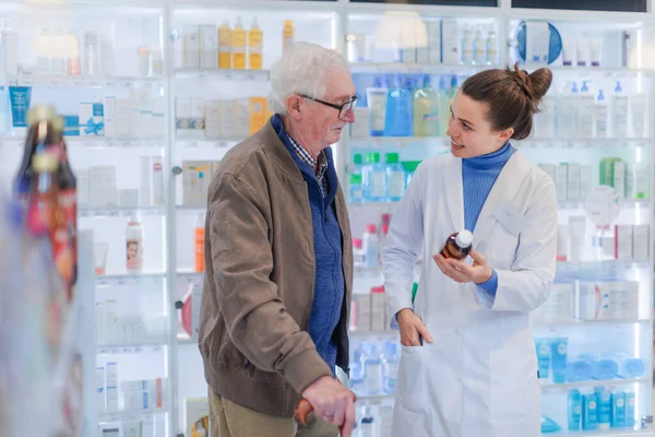 帮助老年人选择药物的年轻药剂师 — 图库照片