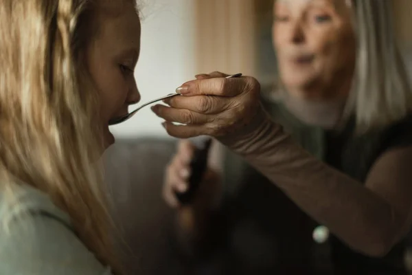 病気の孫娘の世話をするシニア女性 — ストック写真