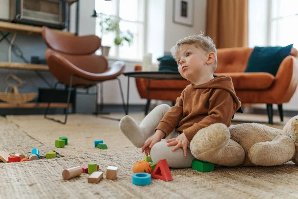 小さな男の子はカーペットの上に座ってキューブと遊ぶ — ストック写真
