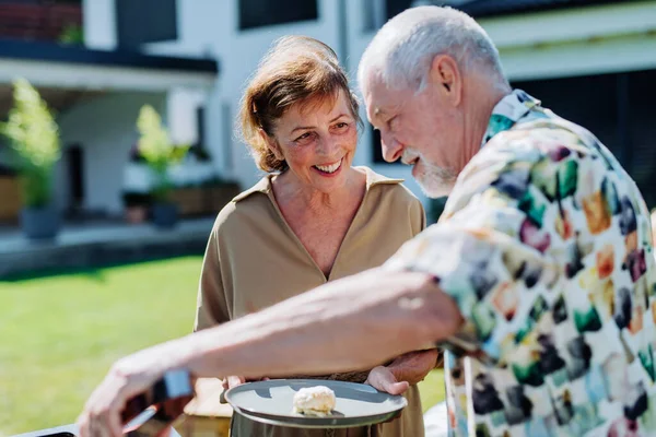 Senior Man Grilled Outdoor Garden Giving His Wife Fresh Hamburger — Stock fotografie