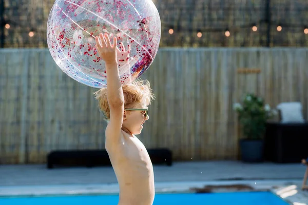 小男孩在自家后院的游泳池边玩充气球 — 图库照片