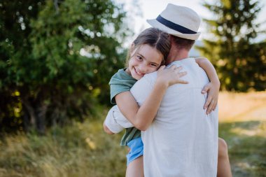 A father hugging his daughter in summer in nature. Fathers day concept.