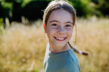 A portrait of a beautiful little girl laughing when having fun in summer in nature.