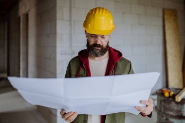 Portrait of mature man working in his new unfinished house. clipart