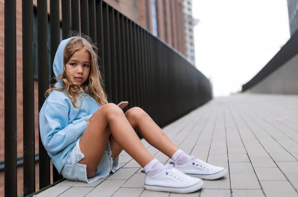 Little Blond Girl Hood Sitting Sidewalk Holding Smartphone Looking Camera — Fotografia de Stock