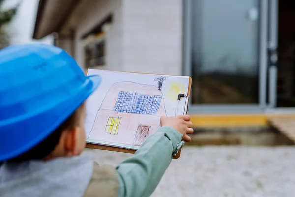 Маленький Мальчик Нарисованной Картинкой Перед Новым Незаконченным Домом — стоковое фото