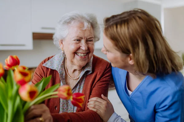 Seniorin Und Krankenschwester Mit Einem Tulpenstrauß — Stockfoto