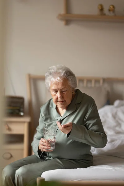 Yaşlı Kadın Yatağında Oturup Ilaç Alıyor — Stok fotoğraf