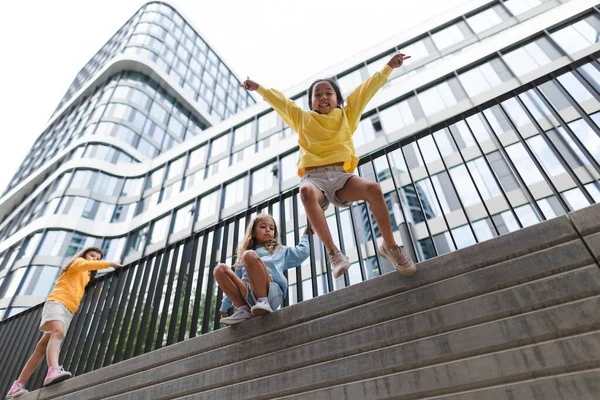 Two Girls Firends Jumping Concrete Wall City Low Angle View — Stockfoto