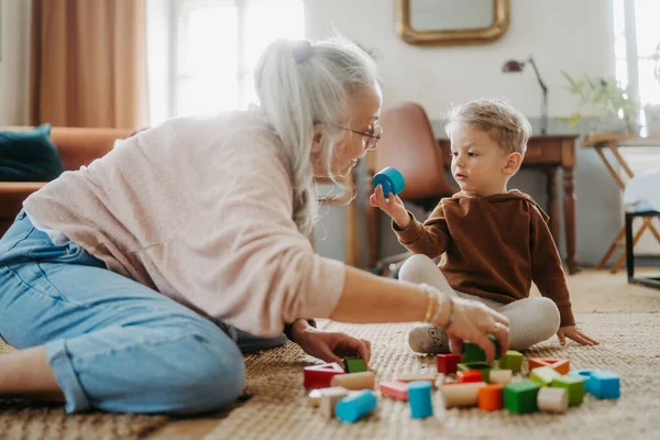 Großmutter Spielt Mit Ihrem Kleinen Enkel Und Baut Einen Holzklotz — Stockfoto