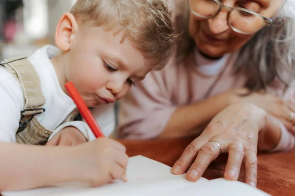 Grandson Drawing Notepad His Grandmother Focused Child Drawning Crayons — Stock Photo, Image