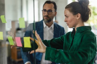 Ofiste meslektaşına notlar gösteren genç bir kadın..