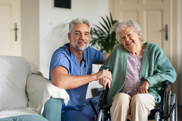 照顾者在家中对资深客户进行定期检查 照顾坐轮椅的老年病人的多得很的男护士 — 图库照片