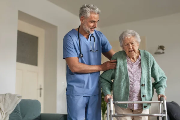 Φροντιστής Βοηθά Ηλικιωμένη Γυναίκα Περπατήσει Στο Σπίτι Της Στοχαστικός Νοσοκόμος — Φωτογραφία Αρχείου