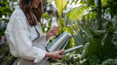 Seradaki bitkilerle ilgilenen genç bahçıvanın portresi..