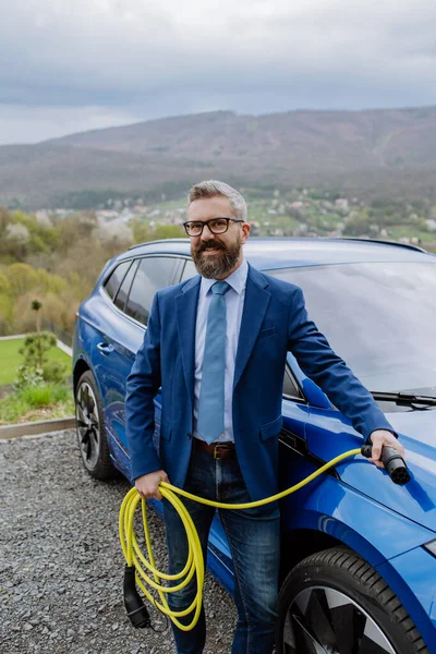 Zbliżenie Biznesmena Trzymającego Kabel Zasilający Nowego Samochodu Elektrycznego — Zdjęcie stockowe